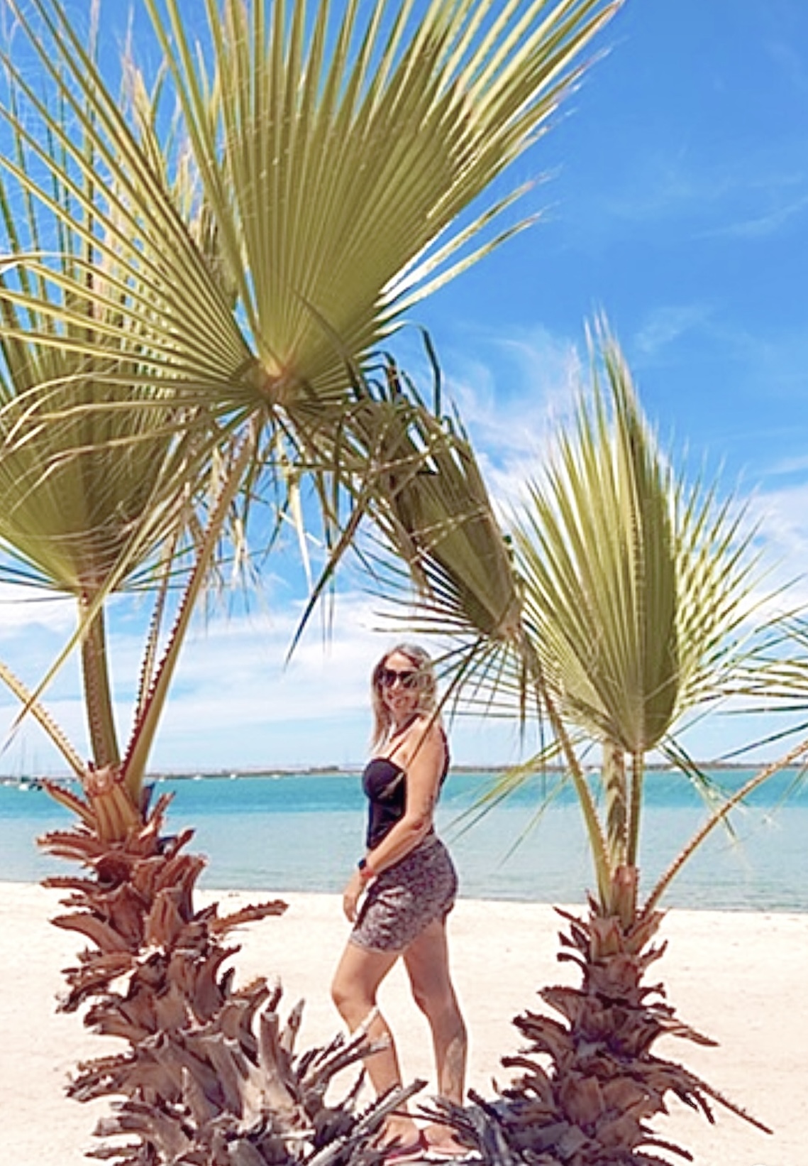 moi à la plage entre 2 palmiers