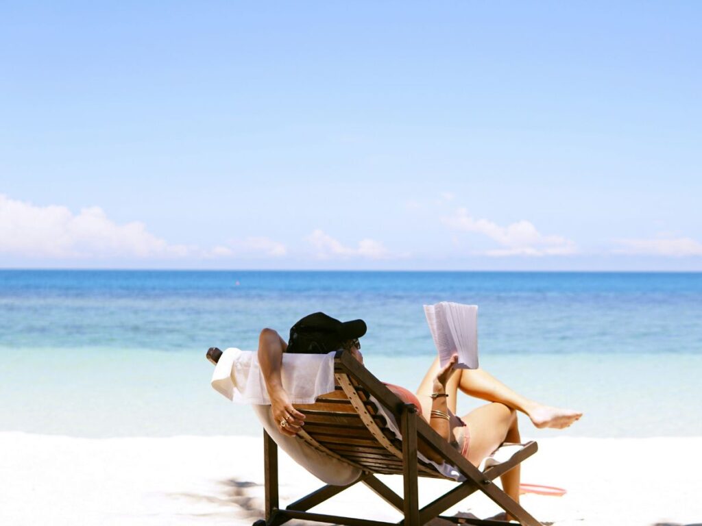 Femme en train de lire, sur un transat, à la plage