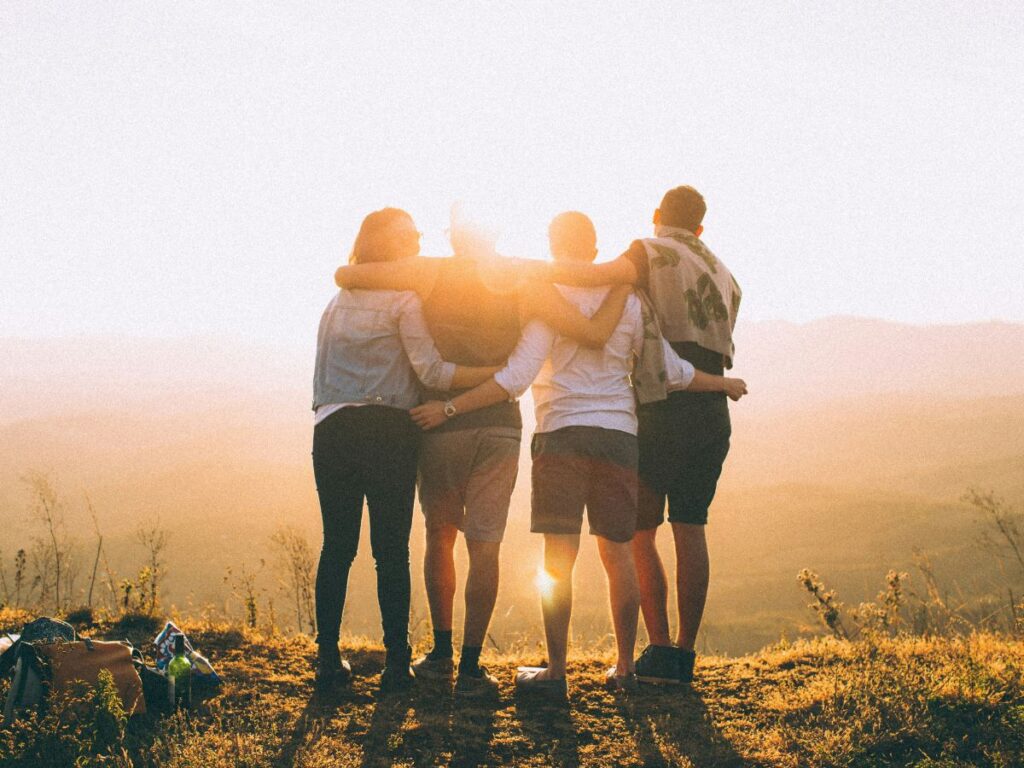 des amis se prennent dans les bras devant le sunset